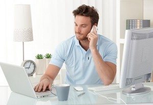 Casual businessman working at office desk, using mobile phone an